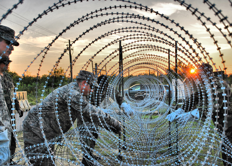 Airmen from the 621st Contingency Response Wing at McGuire Air Force Base, N.J., construct razor wire fences around their camp perimeter June 24 during a noncombatant evacuation exercise at Mackall Army Airfield, N.C.  CRW Airmen manned defensive fighting positions as the exercise scenario became "hostile." (U.S. Air Force photo/Staff Sgt. Nicholas Phelps)